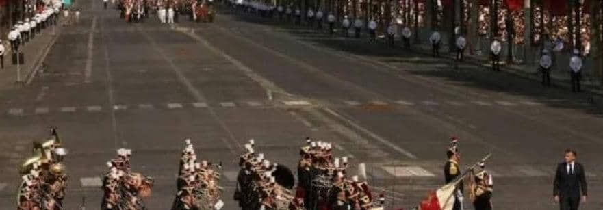 Colonne de soldats défilant sur une large avenue parisienne bordée de spectateurs