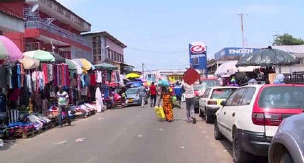 Rue animée de Libreville bordée de commerces et d'étals