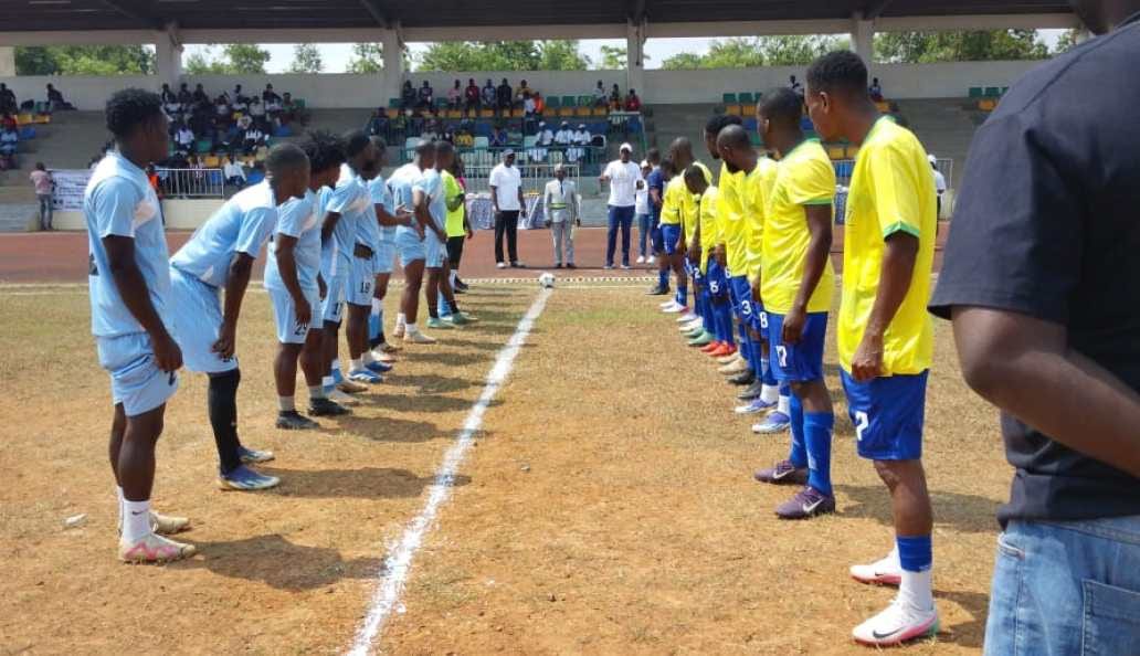Joueurs et officiels rassemblés sur un terrain de football lors d'une cérémonie de lancement