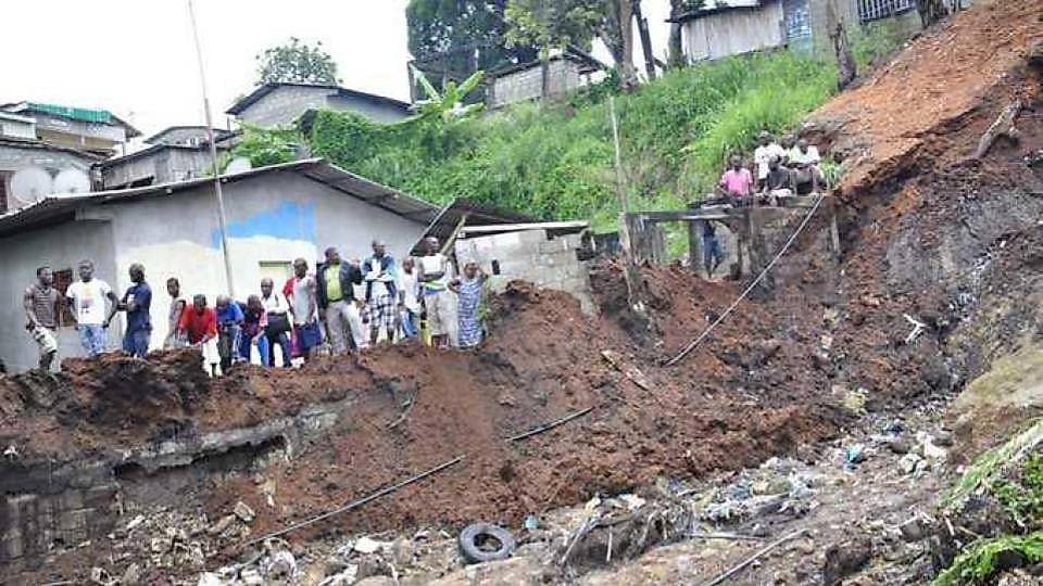 Habitations construites sur une pente fragile à Libreville, sous un ciel de pluie.