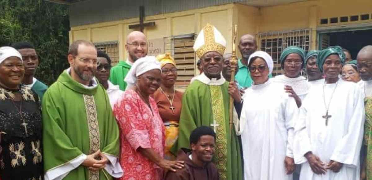 Chapelle rurale au Gabon avec des fidèles réunis devant l'édifice pour une célébration religieuse