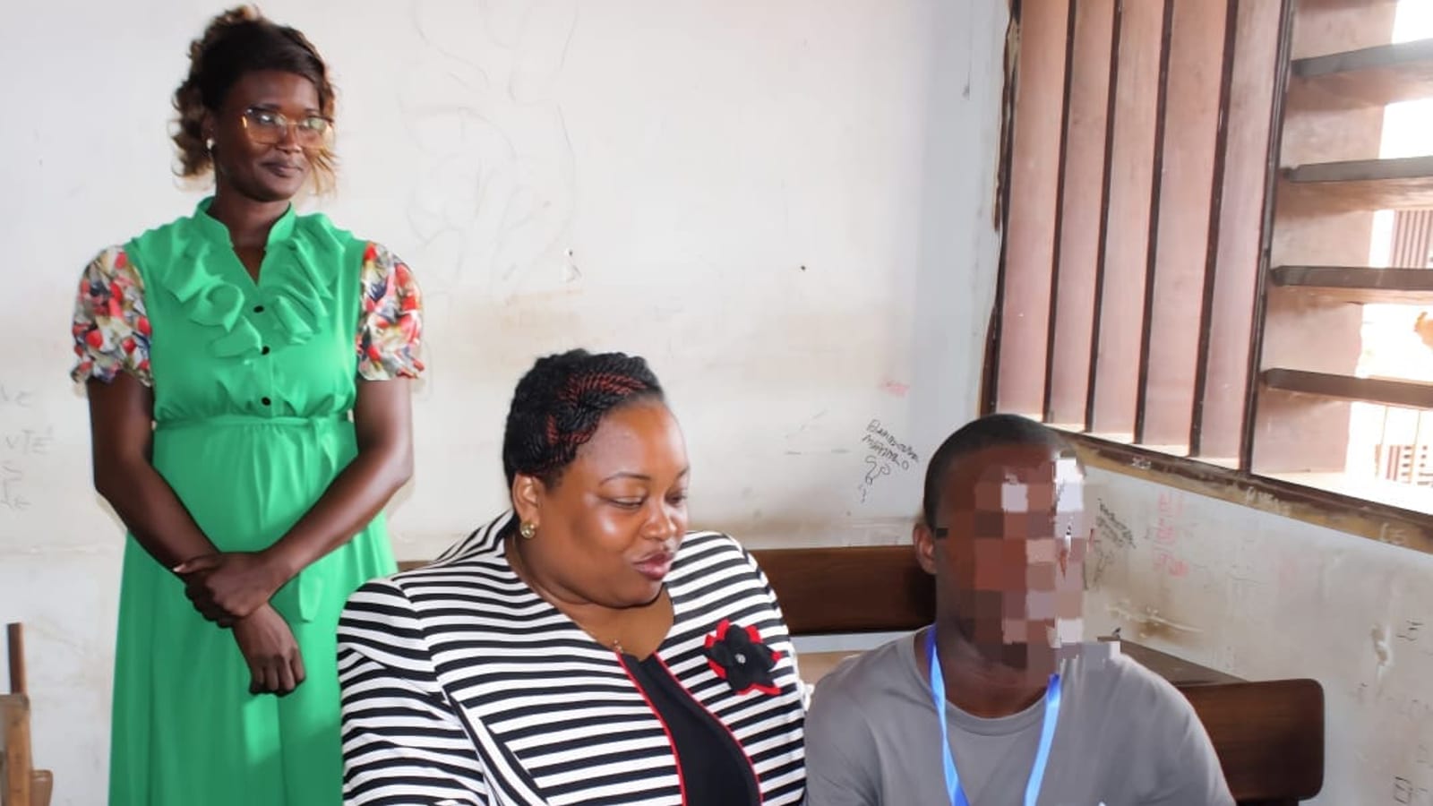 Candidat vivant avec un handicap composant lors d'un examen national au Gabon, accompagné d'un encadrant