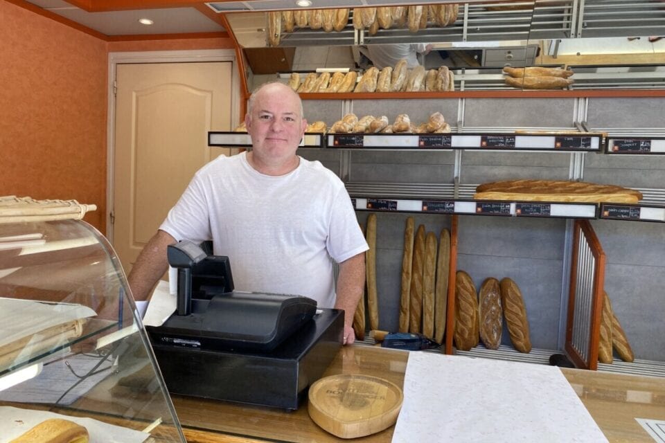 Un boulanger place des baguettes dans un four de boulangerie