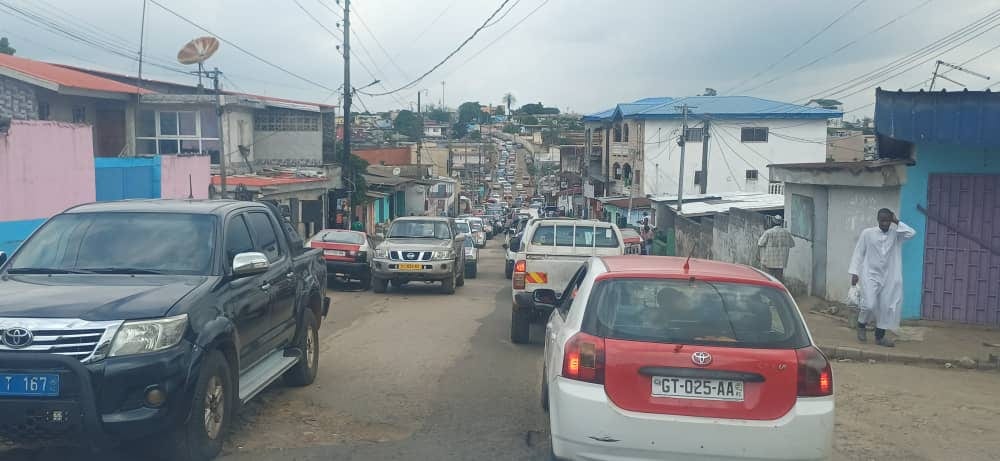 Trottoir encombré à Libreville avec des piétons marchant sur la route