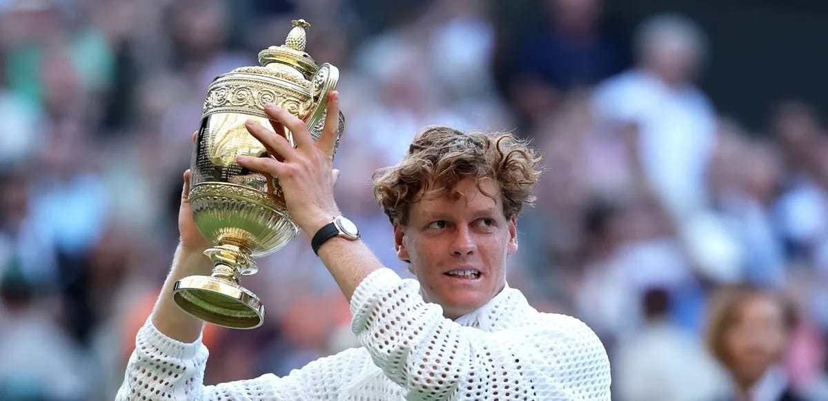 Le joueur de tennis italien Jannik Sinner brandissant un trophée sur un court de tennis en gazon