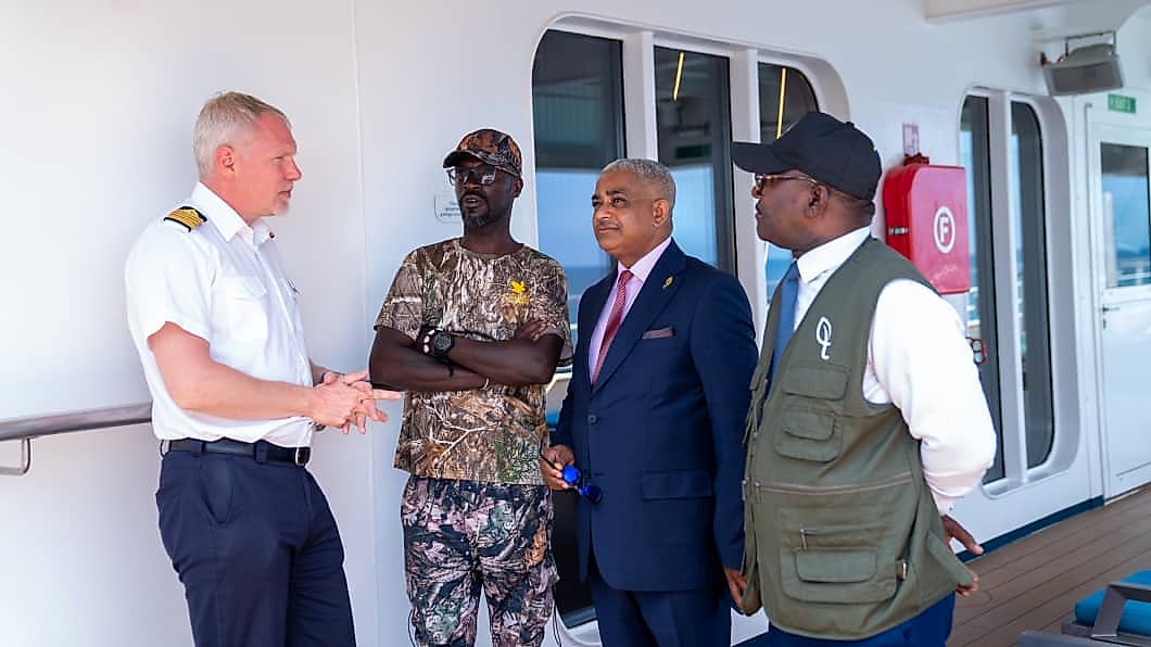 Navire de croisière d'expédition au large d'une côte gabonaise bordée de forêt.