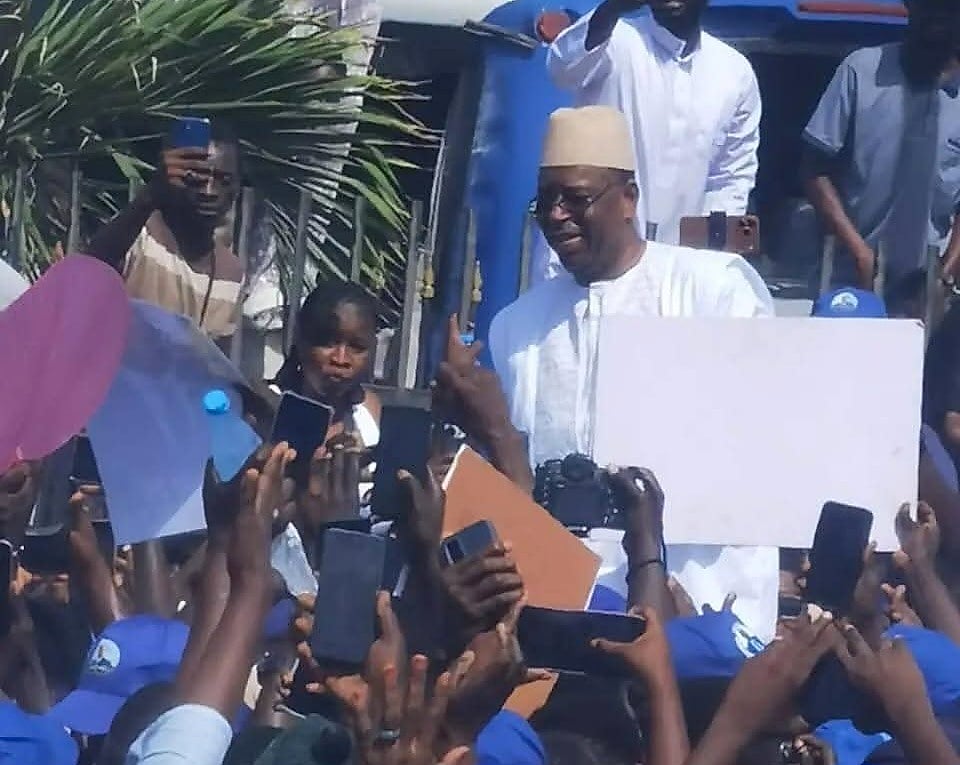Foule en liesse avec drapeaux sénégalais devant un aéroport