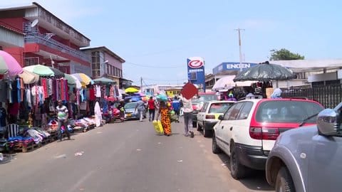 Rue animée de Libreville bordée de commerces et d'étals en plein air