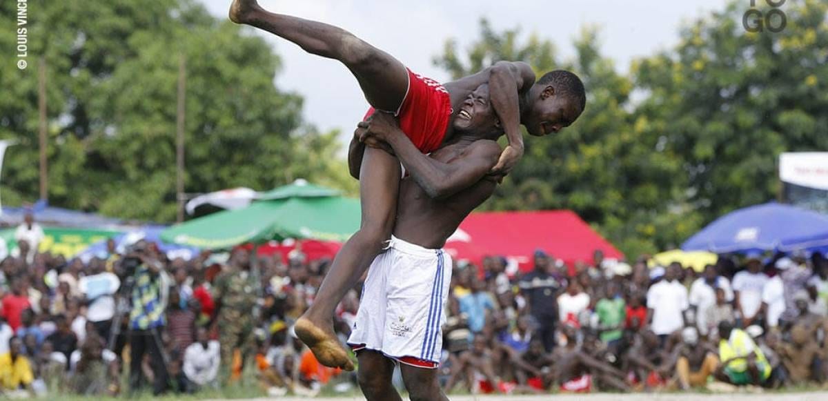 Foule assistant à une lutte traditionnelle en extérieur dans un village d'Afrique de l'Ouest