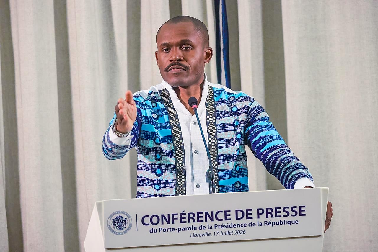 Salle de presse du Palais présidentiel gabonais avec journalistes installés.