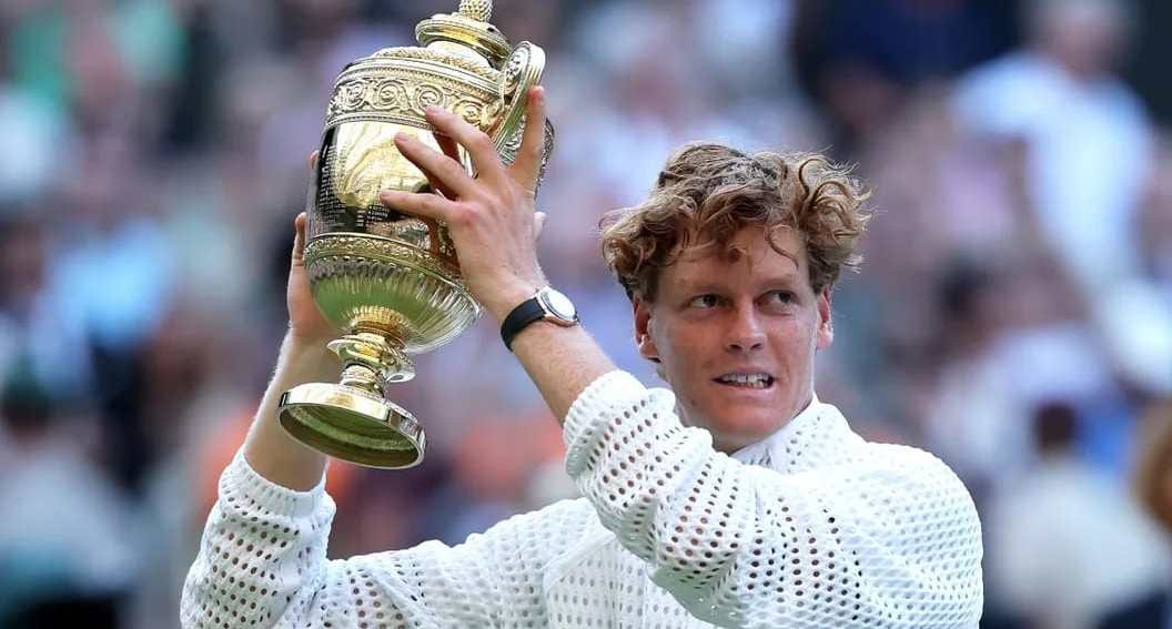 Le joueur de tennis italien Jannik Sinner brandissant un trophée sur un court de tennis en gazon