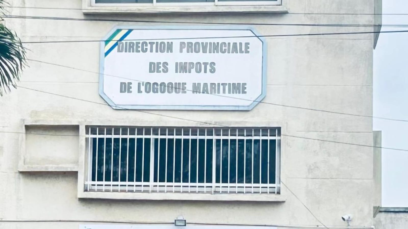 Agent de l'administration fiscale échangeant avec un commerçant dans une rue commerçante de Port-Gentil
