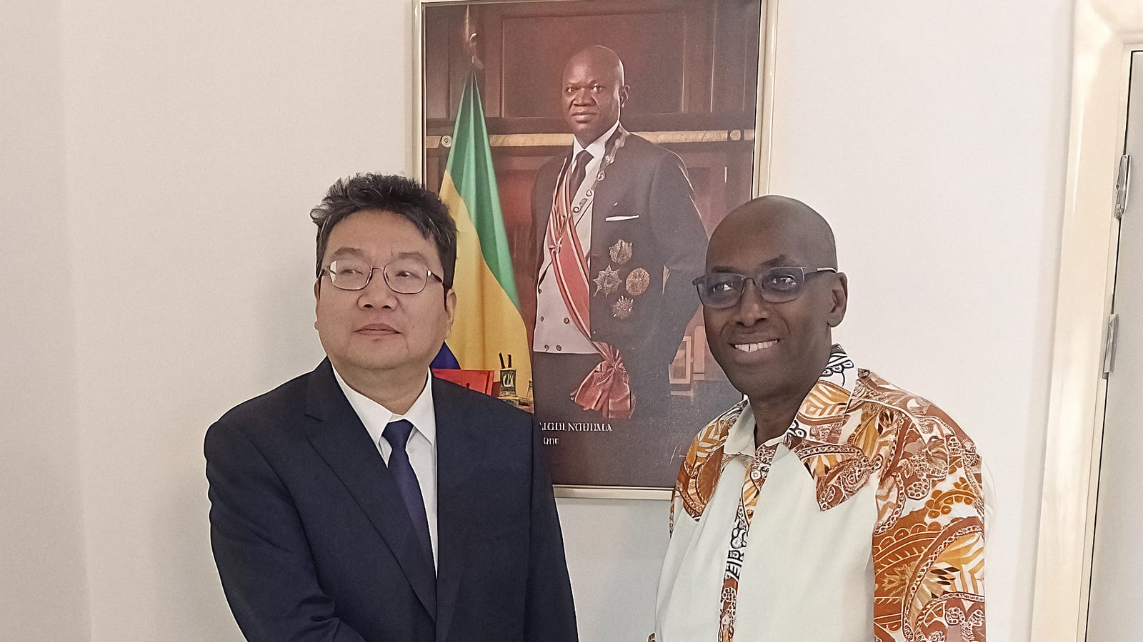 Deux hommes en costume se serrant la main devant des drapeaux du Gabon et de la Chine