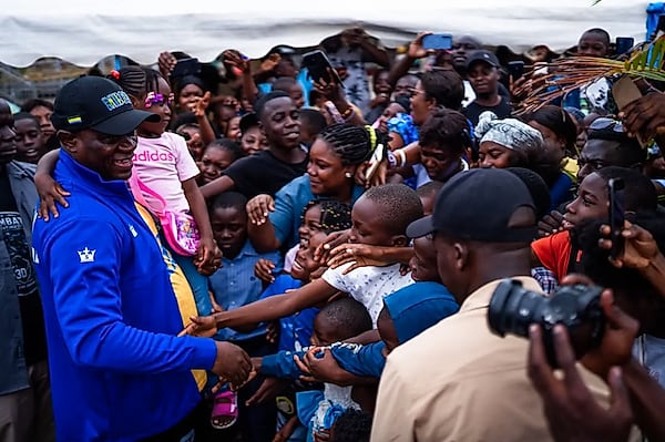Le président de la République entouré d'enfants portant des cartables lors d'une remise de kits scolaires.