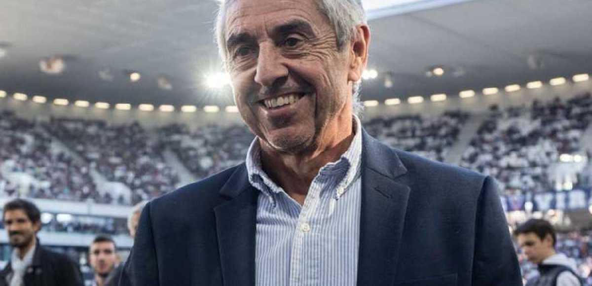 Un entraîneur de football observe le terrain depuis le banc de touche