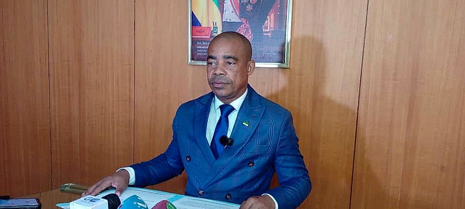 Smartphone affichant des applications de réseaux sociaux devant un bâtiment public gabonais