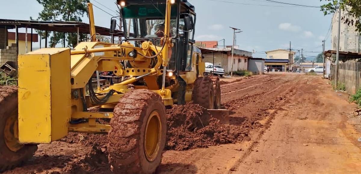 Engin de chantier reprofilant une route en terre latérite dans une commune gabonaise