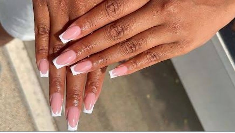 Mains de femme en pose de vernis semi-permanent sous une lampe UV dans un salon de manucure