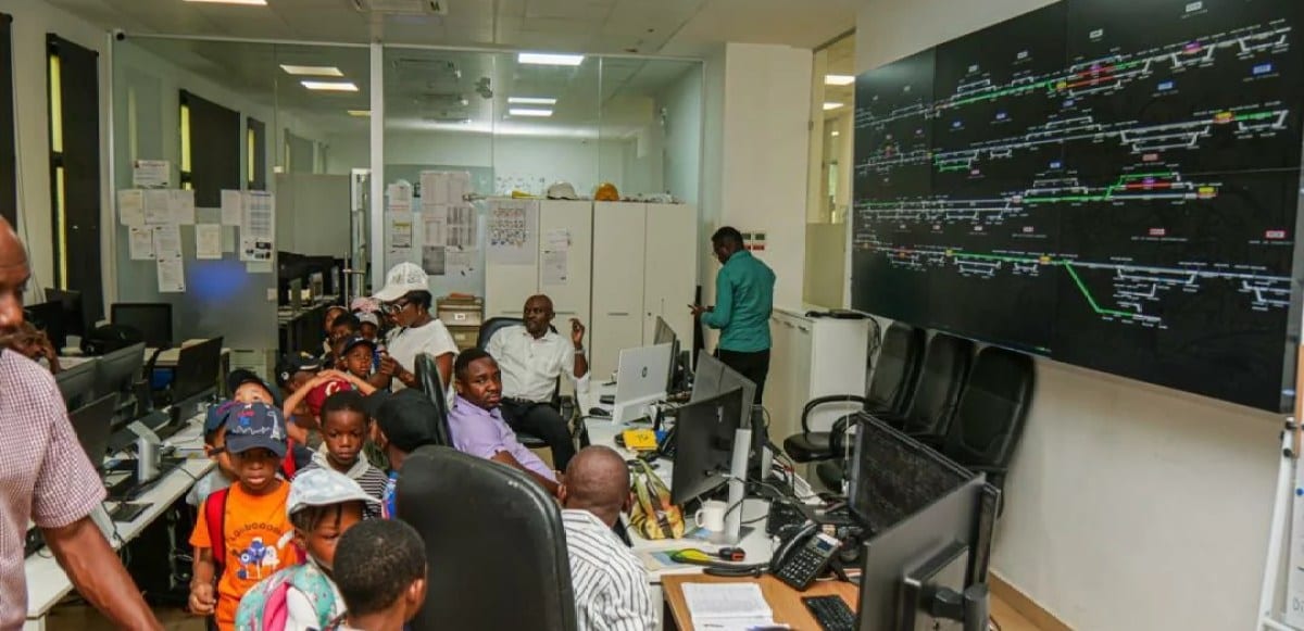 Écoliers gabonais visitant des installations ferroviaires avec un agent de la SETRAG