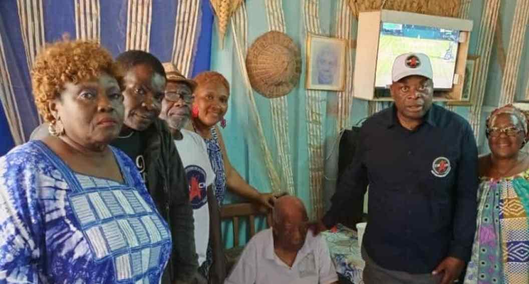 Un centenaire assis, entouré de membres d'une association venus lui rendre visite