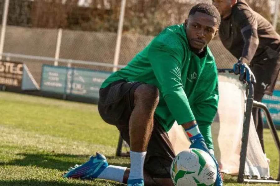 Un gardien de but plonge pour arrêter un ballon dans un stade illuminé