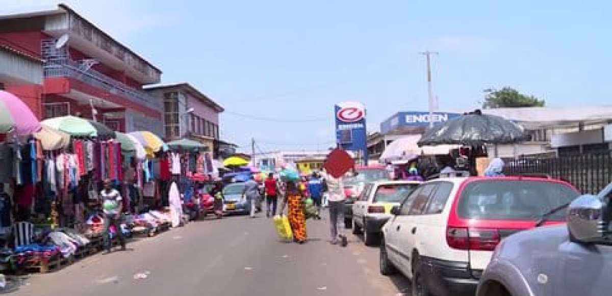 Rue animée de Libreville bordée d'étals et de commerces informels sur le trottoir