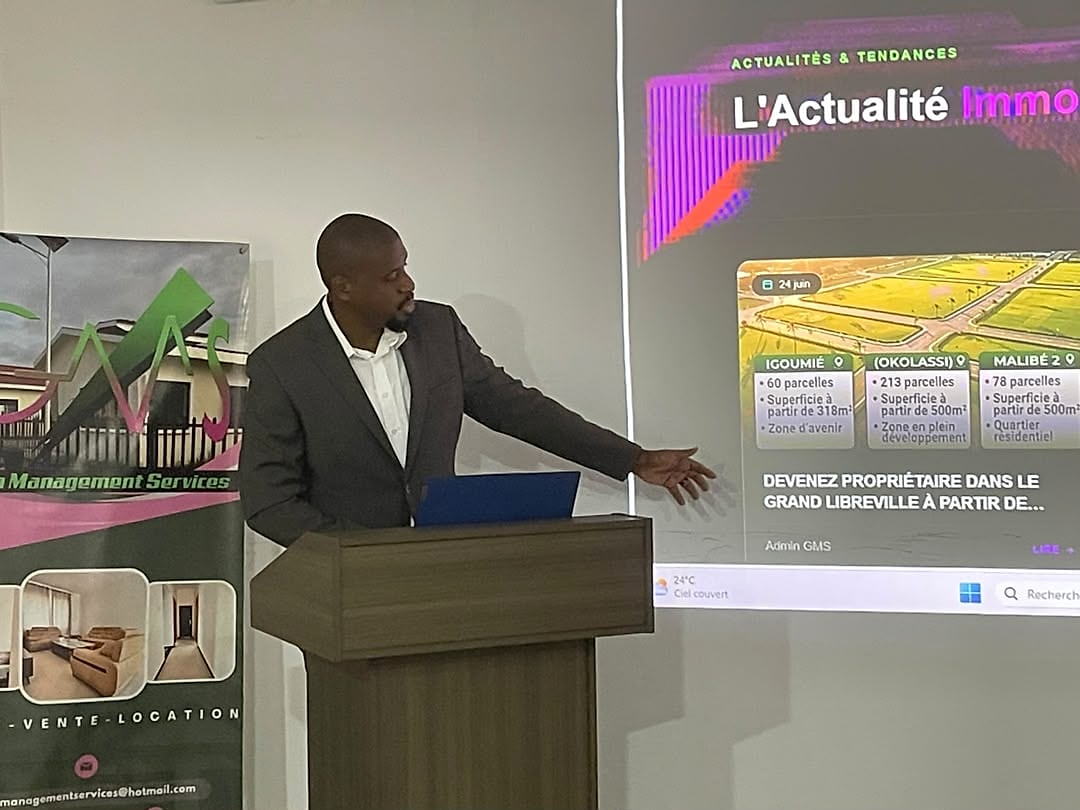 Écran d'ordinateur montrant une page web dédiée à l'immobilier, avec des maisons en arrière-plan.