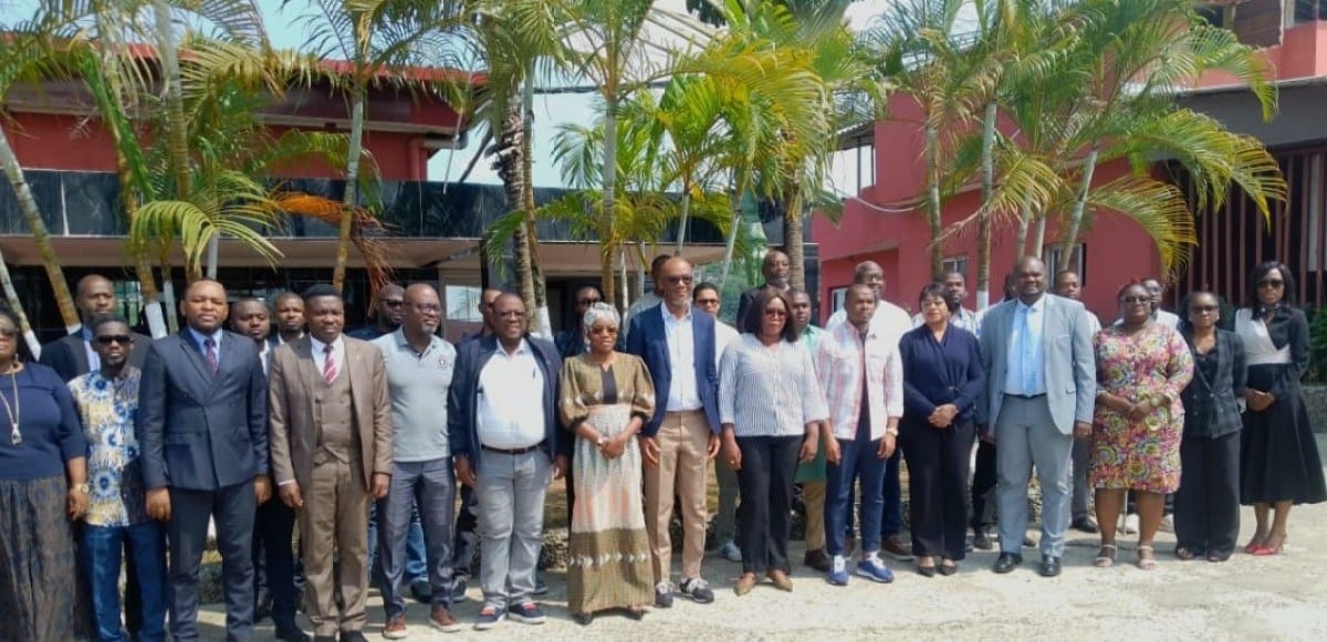 Cadres administratifs assis en atelier de travail, ordinateurs et documents sur une table.